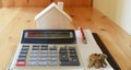 Paper notebook with calculator, house model, keys and pen on wooden table. Royalty Free Stock Photo