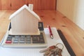 Paper notebook with calculator, house model, keys and pen on wooden table. Royalty Free Stock Photo