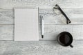 Paper notebook,pen and Cup of tea or coffee and optical glasses on vintage shabby white wooden background. the view from the top.