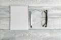 Paper notebook,pen and optical glasses on vintage shabby white wooden background. the view from the top. flat lay