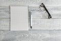 Paper notebook,pen and optical glasses on vintage shabby white wooden background. the view from the top. flat lay