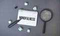 Paper notepad with text MINFULNESS crumpled papers sheets and magnifier glass on dark background Royalty Free Stock Photo