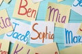 Paper notes with different baby names on light blue wooden table, flat lay