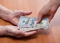 Paper notes in the hands of an old woman. Handing over money