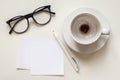 Paper notes mockup, blank space, empty coffee cup, eyeglasses and pen on white desk, overhead flat lay Royalty Free Stock Photo