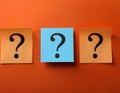 Paper notes with question marks on orange background, flat lay. Space for text Royalty Free Stock Photo