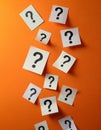 Paper notes with question marks on orange background, flat lay. Space for text Royalty Free Stock Photo