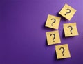 Paper notes with question marks on Violet background, flat lay. Space for text Royalty Free Stock Photo