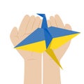 Paper crane in colors of Ukrainian flag on open childrens hands. Concept against war in Ukraine with Japanese symbol of peace and
