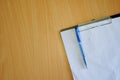 Paper and pen placed on the file on the wooden table, on topview from the right