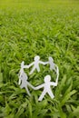 Paper people in a circle with green grass background Royalty Free Stock Photo