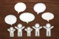Paper people with colorful blank dialog speech bubbles on brown wood. Communication concept.