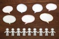 Paper people with colorful blank dialog speech bubbles on brown wood. Communication concept. Royalty Free Stock Photo