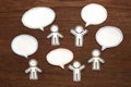 Paper people with colorful blank dialog speech bubbles on brown wood. Communication concept.