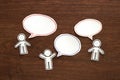 Paper people with colorful blank dialog speech bubbles on brown wood. Communication concept. Royalty Free Stock Photo