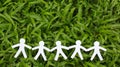 Paper people in a line with green grass background Royalty Free Stock Photo