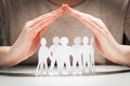 Paper people under hands in gesture of protection Royalty Free Stock Photo