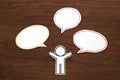 Paper person with colorful blank dialog speech bubbles on brown wood. Communication concept. Royalty Free Stock Photo