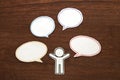 Paper person with colorful blank dialog speech bubbles on brown wood. Communication concept.