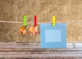 Paper photo frame and dry rose on clothesline Royalty Free Stock Photo