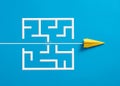 Paper plane breaking through the maze on blue background Royalty Free Stock Photo