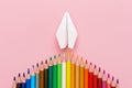 Paper plane, wood colored pencils, flat dip on pink background, top view. Royalty Free Stock Photo