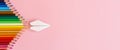 Paper plane, wood colored pencils, flat dip on pink background, top view. Royalty Free Stock Photo