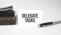 Paper plate, glasses, notepad in stack,pen and text delegate tasks on business card