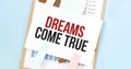 Paper plate with text Dreams Come True. Diagram, notepad and blue background Royalty Free Stock Photo