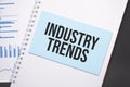 Paper plate with text INDUSTRY TRENDS. Diagram, notepad and blue background Royalty Free Stock Photo