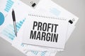 Paper plate with text PROFIT MARGIN. Diagram, notepad and blue background Royalty Free Stock Photo