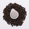 Coffee paper pod dosette for espresso laying on fresh ground coffee beans. on white background