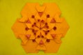 Paper quilling and origami composition. Creative orange hexagon isolated on yellow background.