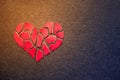 Paper red broken heart on dark felt background. Mosaic paper heart from pieces. Cracked heart symbol. Broken love concept. Copy s