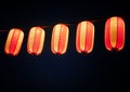 Paper red-white asian japanese chinese lanterns chochin akachochin shines on dark sky. A garland of paper lanterns glows at night Royalty Free Stock Photo