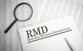 Paper with Required Minimum Distributions RMD on a table with pen ,chart and magnifier Royalty Free Stock Photo
