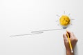 Paper scrap ball yellow colour with light bulb symbol on white background and hand holding yellow pencil Royalty Free Stock Photo