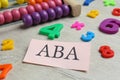 Paper sheet with abbreviation ABA Applied behavior analysis, abacus and colorful numbers on white wooden table, closeup Royalty Free Stock Photo