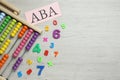 Paper sheet with abbreviation ABA Applied behavior analysis, abacus and colorful numbers on white wooden table, flat lay. Space Royalty Free Stock Photo