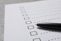 Paper sheet with checkboxes and pen on light grey table, closeup. Checklist Royalty Free Stock Photo