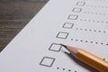 Paper sheet with checkboxes and pencil on wooden table, closeup. Checklist