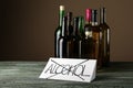 Paper sheet with crossed word ALCOHOL and bottles of drinks on wooden table Royalty Free Stock Photo