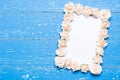 Paper sheet with frame made of roses on painted wood Royalty Free Stock Photo