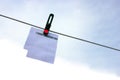 Paper sheet notepad hanging on a rope on clothespins on a light blue background. Royalty Free Stock Photo