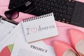 Paper sheet with text I love America and women`s shoes,sun glasses and computer keyboard on bright pink background. Royalty Free Stock Photo