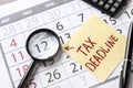 Paper sheet with text TAX DEADLINE and magnifying glass on calendar Royalty Free Stock Photo