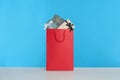 Paper shopping bag full of gift boxes on light blue background Royalty Free Stock Photo
