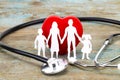 Paper silhouette of family, stethoscope and heart on wooden back Royalty Free Stock Photo