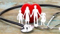 Paper silhouette of family, stethoscope and heart on wooden background. Health insurance concept Royalty Free Stock Photo