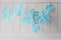 Paper snowflakes hanging on white wooden background. Christmas decoration. Toned Royalty Free Stock Photo